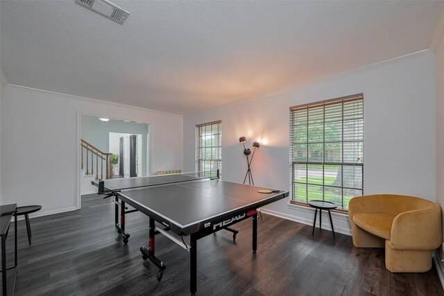 rec room featuring plenty of natural light, dark wood-type flooring, ornamental molding, and baseboards