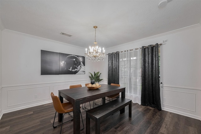 dining room with a chandelier, wood finished floors, crown molding, wainscoting, and a decorative wall