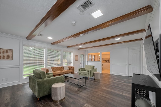 living room with a decorative wall, beamed ceiling, dark wood finished floors, and ornamental molding
