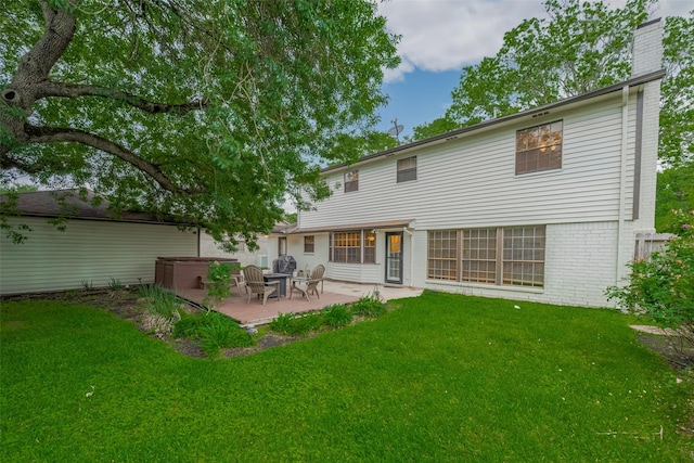 rear view of property with a patio area, brick siding, a yard, and a covered hot tub