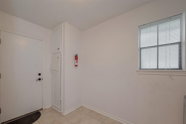 doorway with light tile patterned floors and baseboards