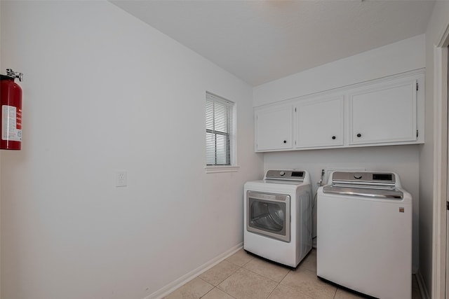 washroom featuring cabinet space, independent washer and dryer, baseboards, and light tile patterned floors