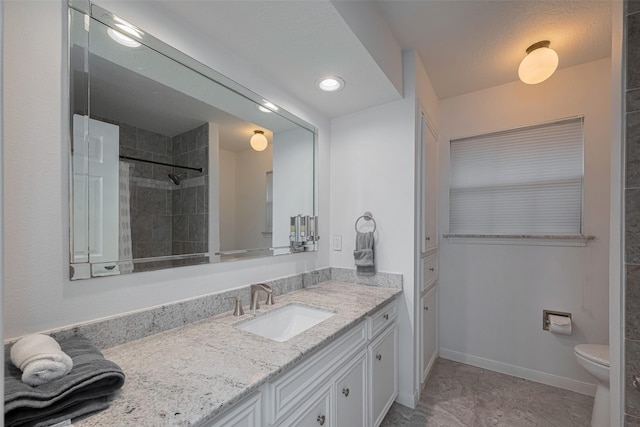 full bathroom featuring vanity, a tile shower, toilet, and baseboards