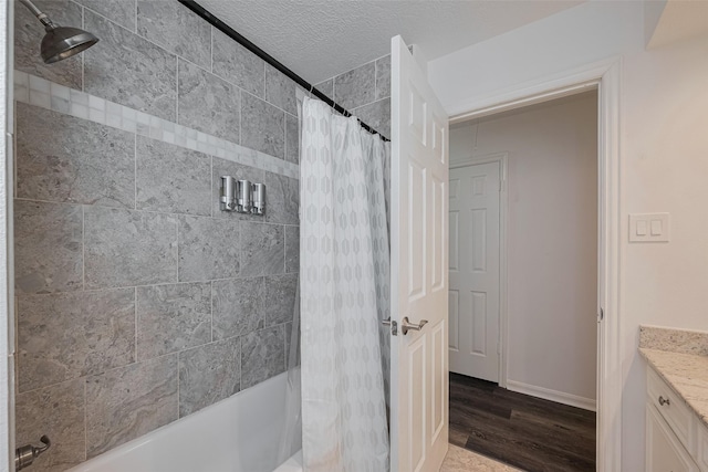 full bath featuring wood finished floors, shower / bath combination with curtain, a textured ceiling, baseboards, and vanity