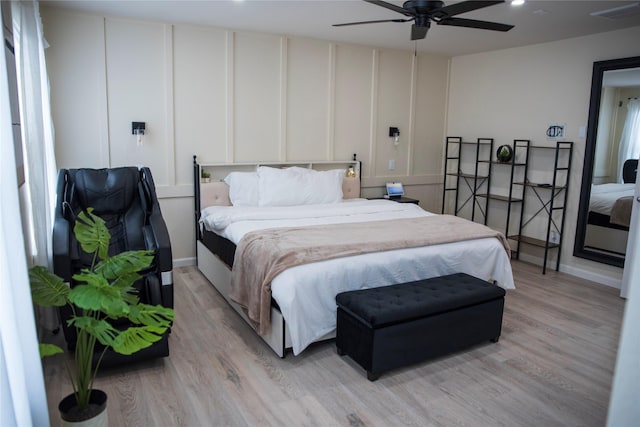 bedroom featuring light wood finished floors, a decorative wall, and visible vents