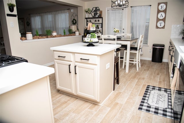 kitchen with a kitchen island, a chandelier, light wood-style flooring, and light countertops