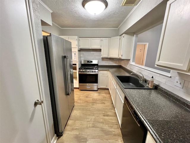 37 Ranch House Loop, Angleton, TX 77515 - kitchen with a sink, a textured ceiling, light wood-style flooring, dark countertops, and appliances with stainless steel finishes