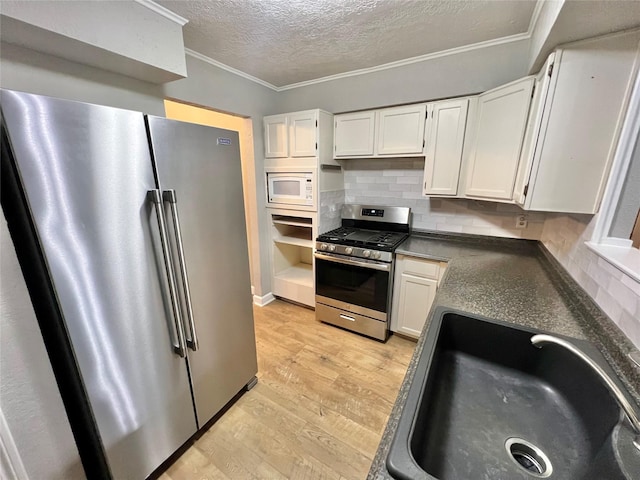 37 Ranch House Loop, Angleton, TX 77515 - kitchen featuring a sink, tasteful backsplash, a textured ceiling, light wood-type flooring, and appliances with stainless steel finishes