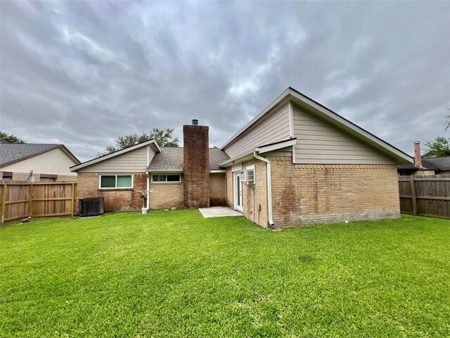 37 Ranch House Loop, Angleton, TX 77515 - rear view of property featuring central AC, a chimney, a fenced backyard, a yard, and brick siding
