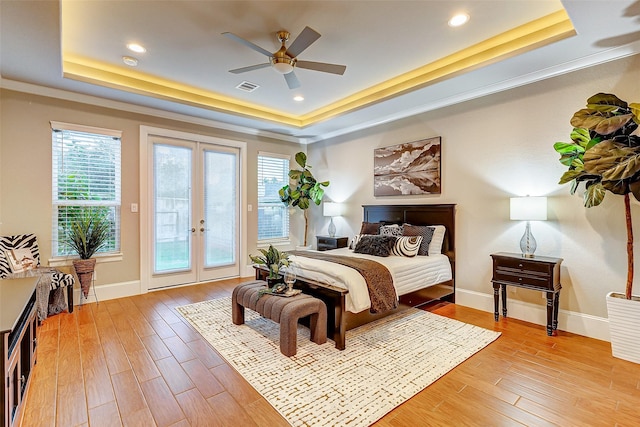 bedroom with french doors, light wood-type flooring, visible vents, a tray ceiling, and access to exterior