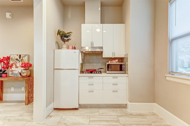 kitchen featuring stainless steel appliances, white cabinets, backsplash, under cabinet range hood, and light countertops