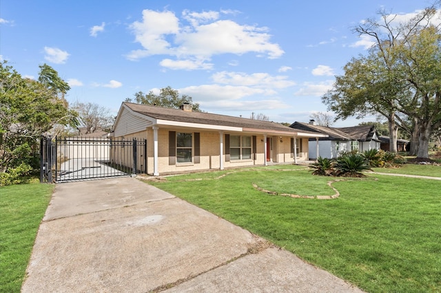 view of front of home featuring a chimney, driveway, brick siding, a front yard, and a gate