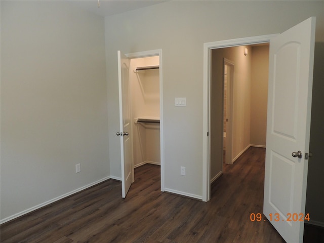 1100 Mann Rd, Conroe, TX 77303 - unfurnished bedroom featuring baseboards, a spacious closet, a closet, and dark wood-type flooring