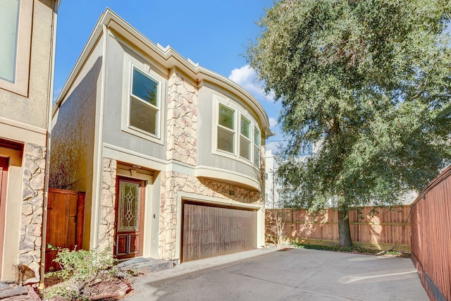 view of front of home with fence, a garage, stucco siding, and stone siding