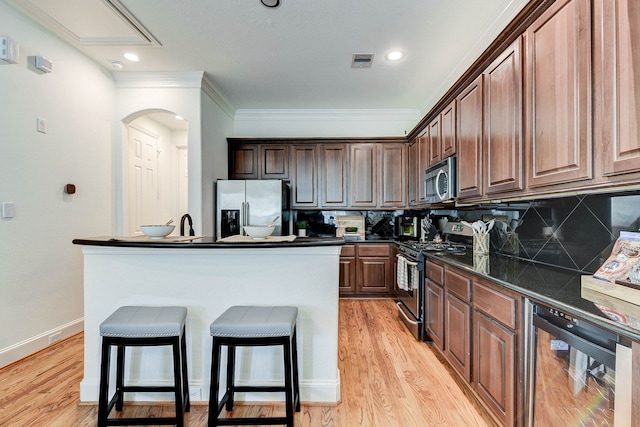 kitchen featuring dark countertops, stainless steel appliances, visible vents, tasteful backsplash, and wine cooler