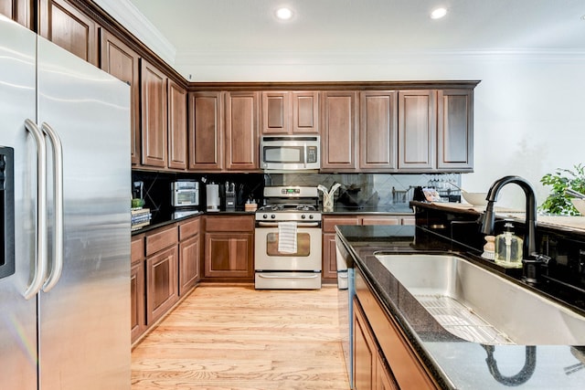 kitchen featuring a sink, crown molding, stainless steel appliances, and light wood finished floors