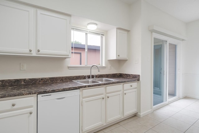 kitchen with white dishwasher, a sink, dark countertops, white cabinetry, and light tile patterned floors