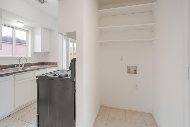 clothes washing area with a sink, hookup for a washing machine, plenty of natural light, and light tile patterned floors