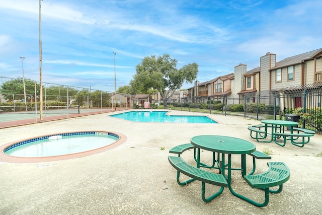 community pool with fence, a residential view, and a patio area