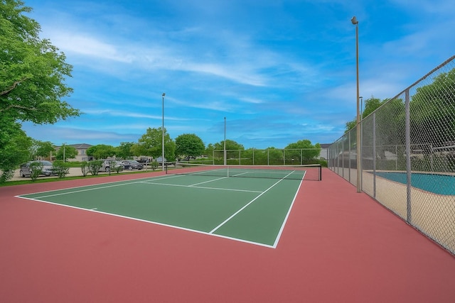 view of tennis court with community basketball court and fence