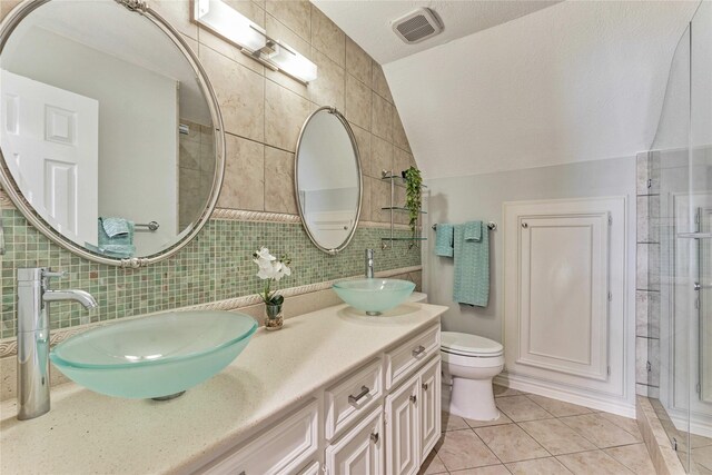 15050 Lake Paula Dr, Willis, TX 77318 - full bathroom with tile walls, tile patterned floors, vaulted ceiling, double vanity, and toilet