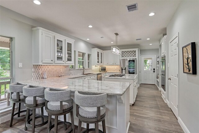 15050 Lake Paula Dr, Willis, TX 77318 - kitchen featuring a peninsula, white cabinets, recessed lighting, tasteful backsplash, and stainless steel appliances