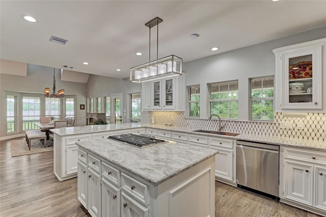 15050 Lake Paula Dr, Willis, TX 77318 - kitchen with stainless steel appliances, a sink, a peninsula, a chandelier, and white cabinetry