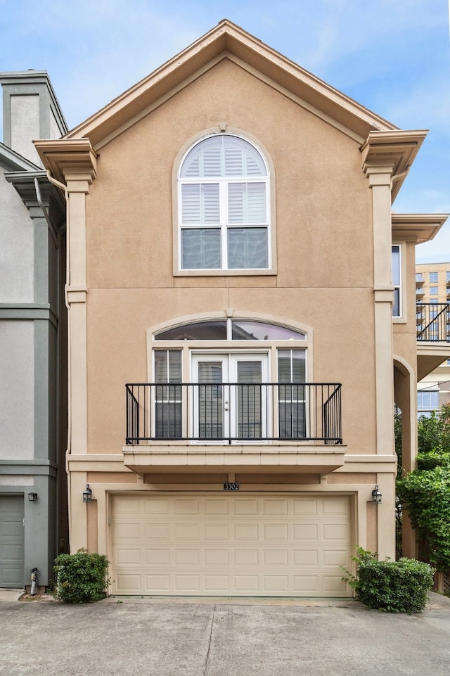 view of property featuring a garage, stucco siding, and a balcony