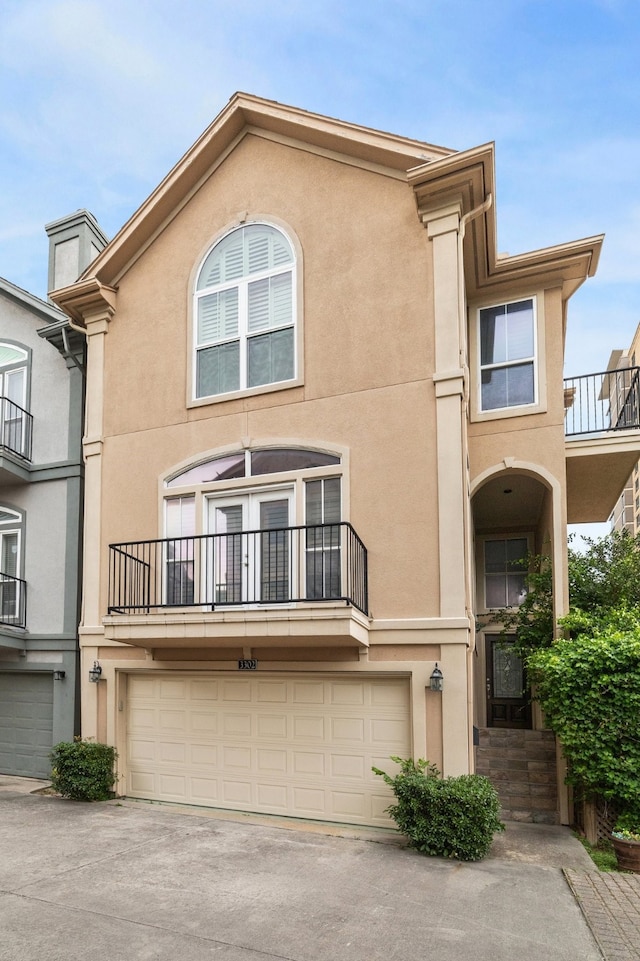 multi unit property featuring an attached garage, stucco siding, driveway, and a balcony