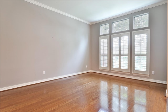 spare room with ornamental molding, baseboards, and wood finished floors