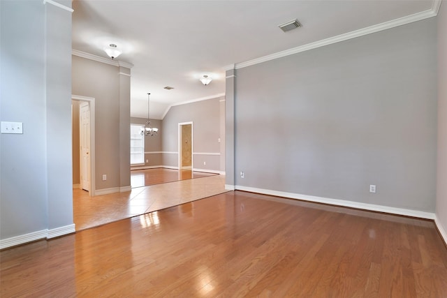 unfurnished room featuring baseboards, ornamental molding, an inviting chandelier, visible vents, and wood finished floors