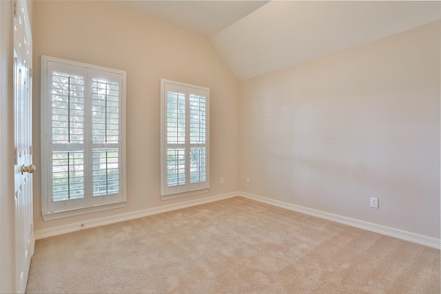 carpeted empty room featuring a wealth of natural light, baseboards, and lofted ceiling