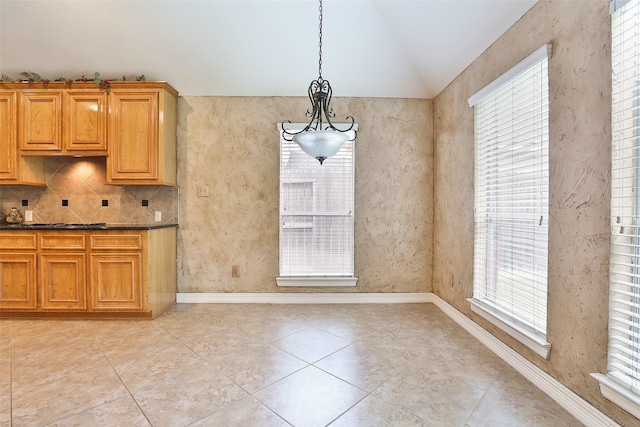 kitchen featuring a wealth of natural light, vaulted ceiling, baseboards, and light tile patterned flooring