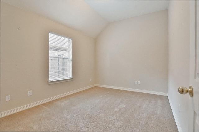 empty room featuring light carpet, baseboards, and lofted ceiling