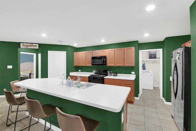 4826 Westfield Pines Dr, Katy, TX 77449 - kitchen with black appliances, washer / dryer, a kitchen breakfast bar, a sink, and recessed lighting