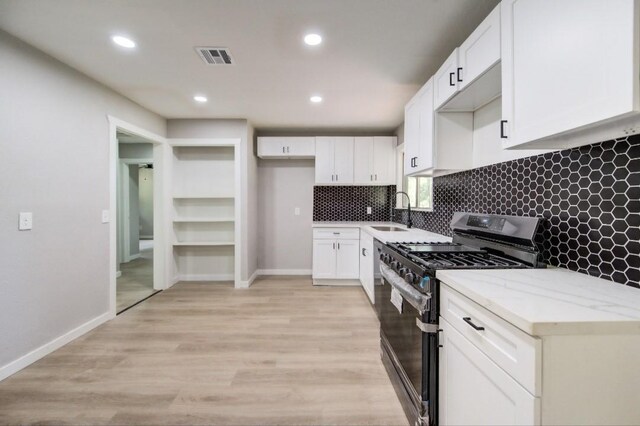 kitchen with white cabinetry, decorative backsplash, stainless steel range with gas stovetop, and a sink
