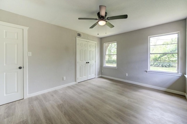 unfurnished bedroom featuring baseboards, a closet, visible vents, and wood finished floors