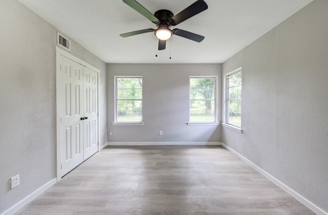 unfurnished bedroom with baseboards, visible vents, a textured wall, and wood finished floors