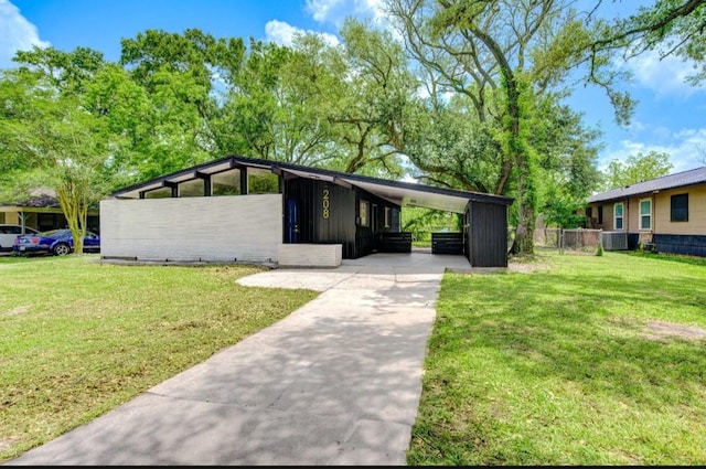 view of front of property with fence, central AC, concrete driveway, a front yard, and a carport