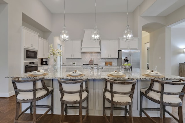 1614 Primrose Ln, Katy, TX 77493 - kitchen featuring appliances with stainless steel finishes, tasteful backsplash, premium range hood, white cabinets, and a large island