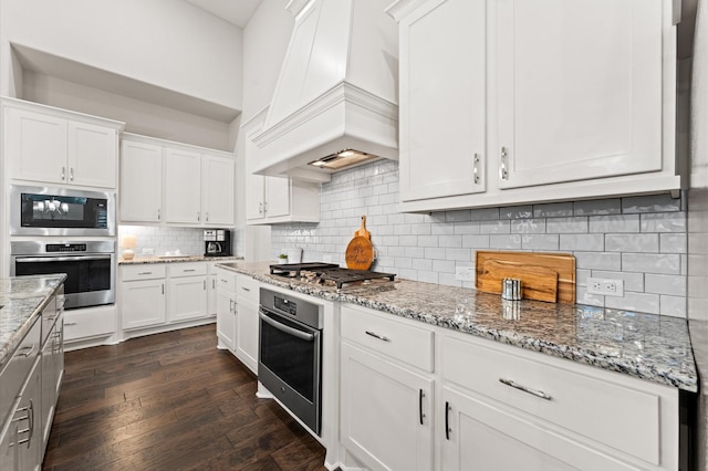 1614 Primrose Ln, Katy, TX 77493 - kitchen with stainless steel appliances, custom range hood, white cabinets, and dark wood-style floors
