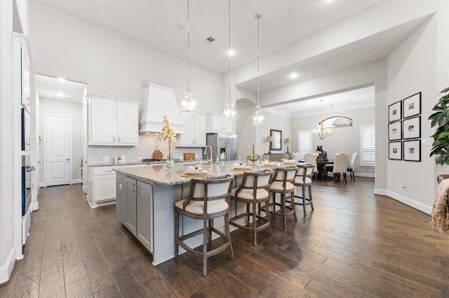 1614 Primrose Ln, Katy, TX 77493 - kitchen with stainless steel appliances, a large island with sink, dark wood-type flooring, a kitchen breakfast bar, and white cabinetry