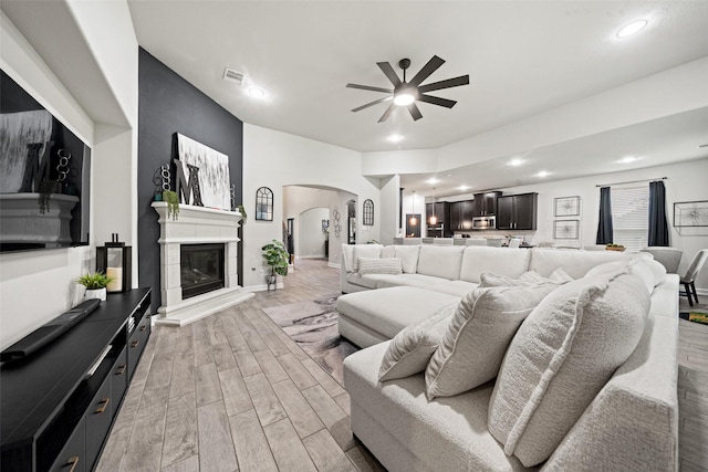 living room with visible vents, recessed lighting, arched walkways, a ceiling fan, and light wood-style floors