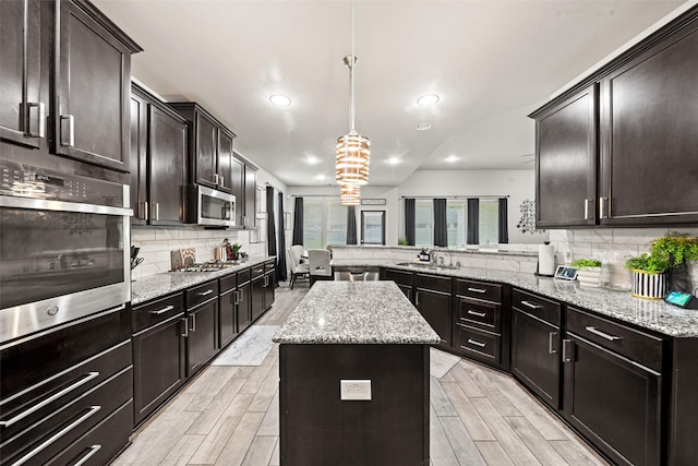 kitchen featuring recessed lighting, a peninsula, decorative backsplash, a kitchen island, and stainless steel appliances