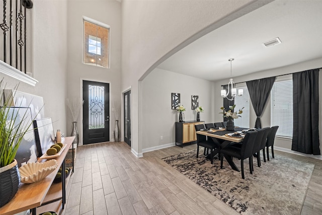 entryway with baseboards, an inviting chandelier, visible vents, wood finished floors, and arched walkways