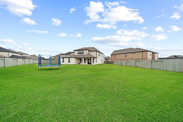 view of yard featuring a trampoline and a fenced backyard