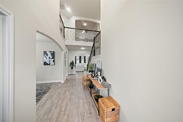 entryway featuring wood finished floors, a high ceiling, visible vents, baseboards, and arched walkways