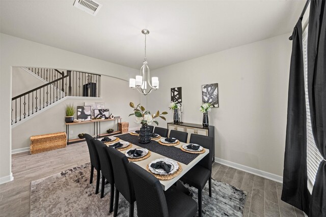 dining room with stairs, wood finished floors, baseboards, visible vents, and a notable chandelier