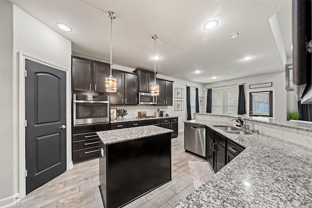 kitchen featuring a sink, stainless steel appliances, decorative light fixtures, light stone counters, and backsplash