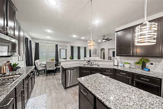 kitchen featuring tasteful backsplash, pendant lighting, ceiling fan, light wood finished floors, and appliances with stainless steel finishes